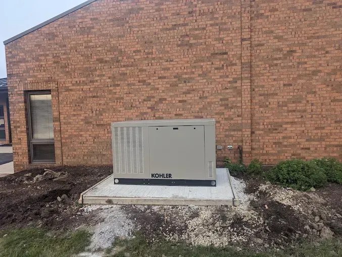 Generator box on a concrete pad next to a brick building.