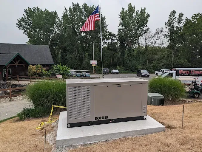 A large Kohler generator on a concrete pad with a flagpole and building in the background.