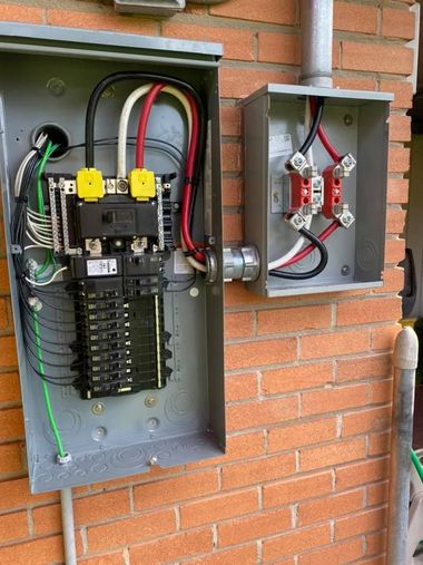 Open electrical breaker panel and meter box mounted on a brick wall