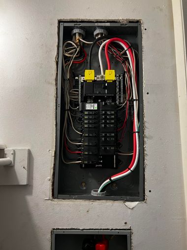 Electrical breaker panel with exposed wiring in a wall opening