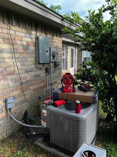 Outdoor HVAC unit beside a brick house, with maintenance tools and a red machine on top.
