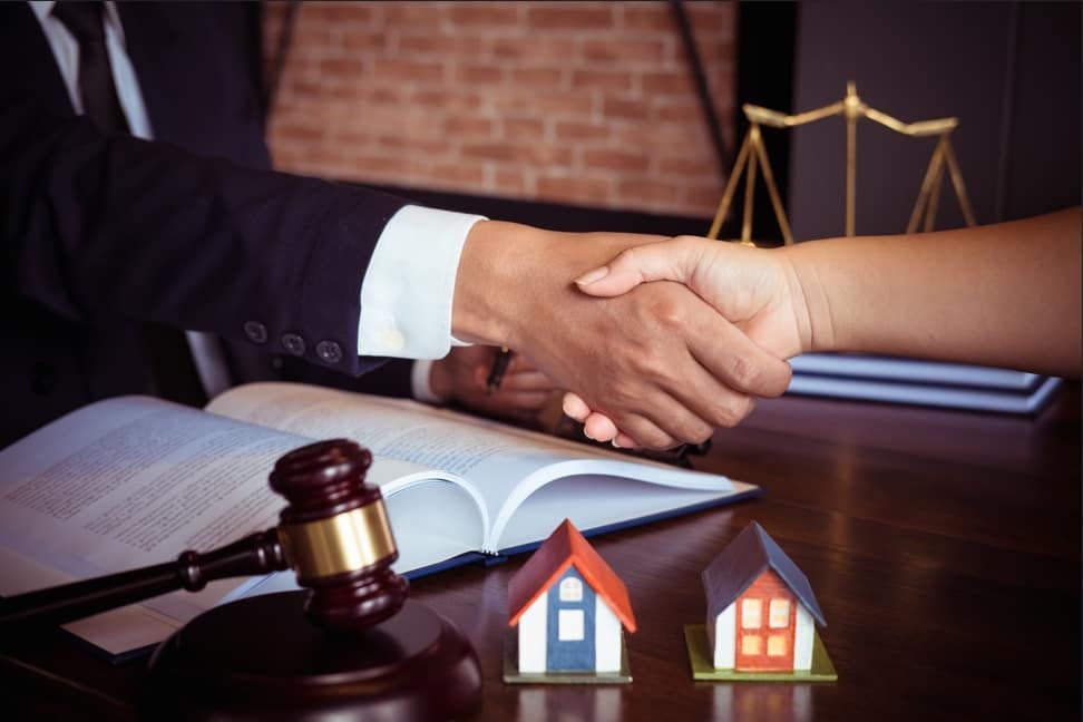 A judge is shaking hands with a client in front of a gavel and scales of justice.