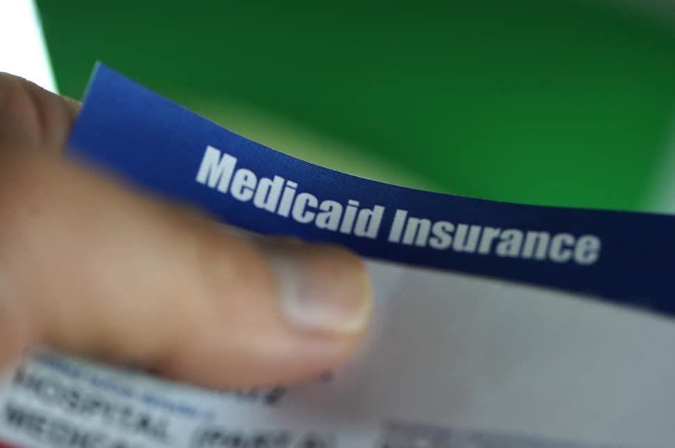 A person is holding a medicaid insurance card