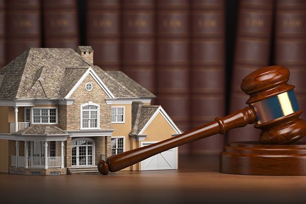 A model house is sitting next to a wooden gavel on a table.