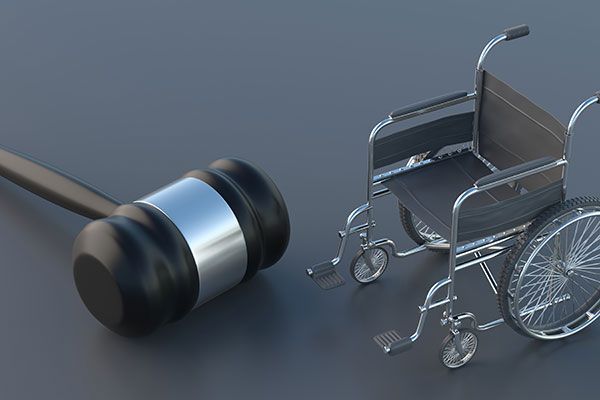 A wheelchair is next to a judge 's gavel on a gray surface.