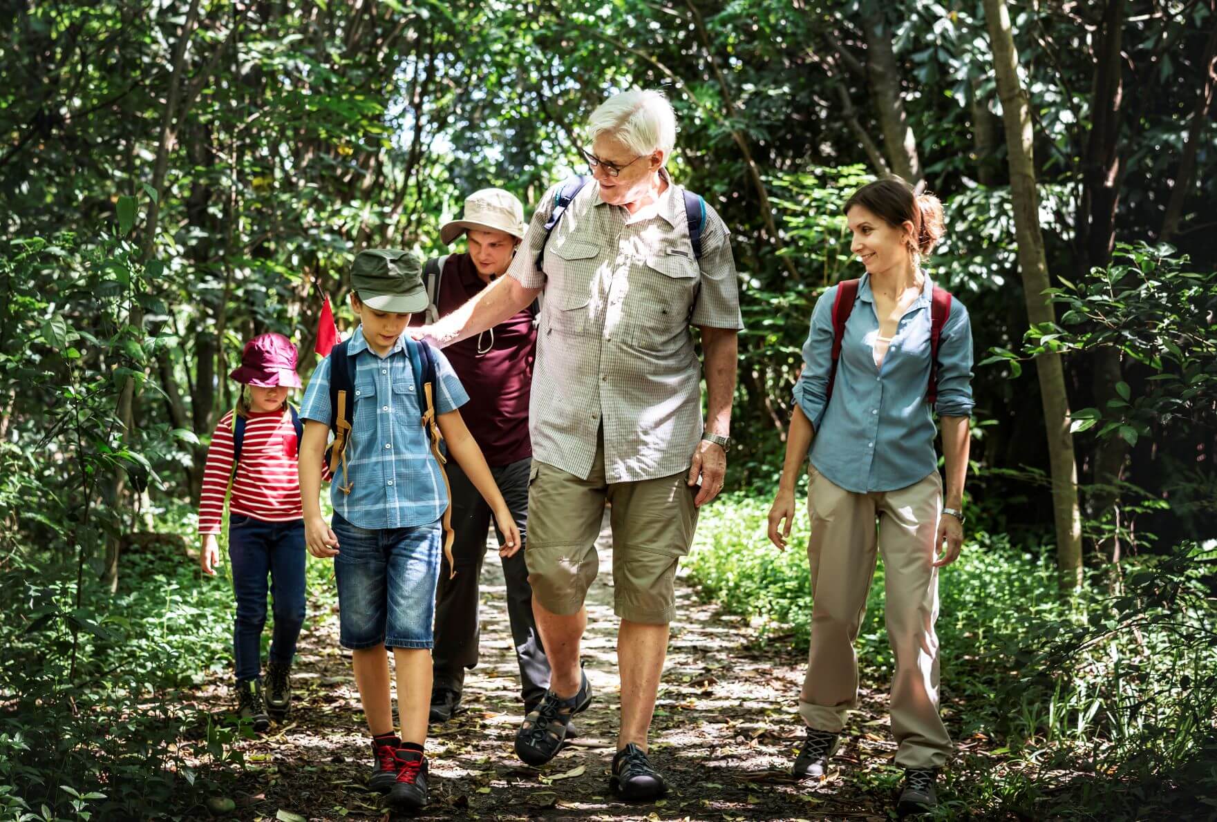 A group of people are walking down a path in the woods.