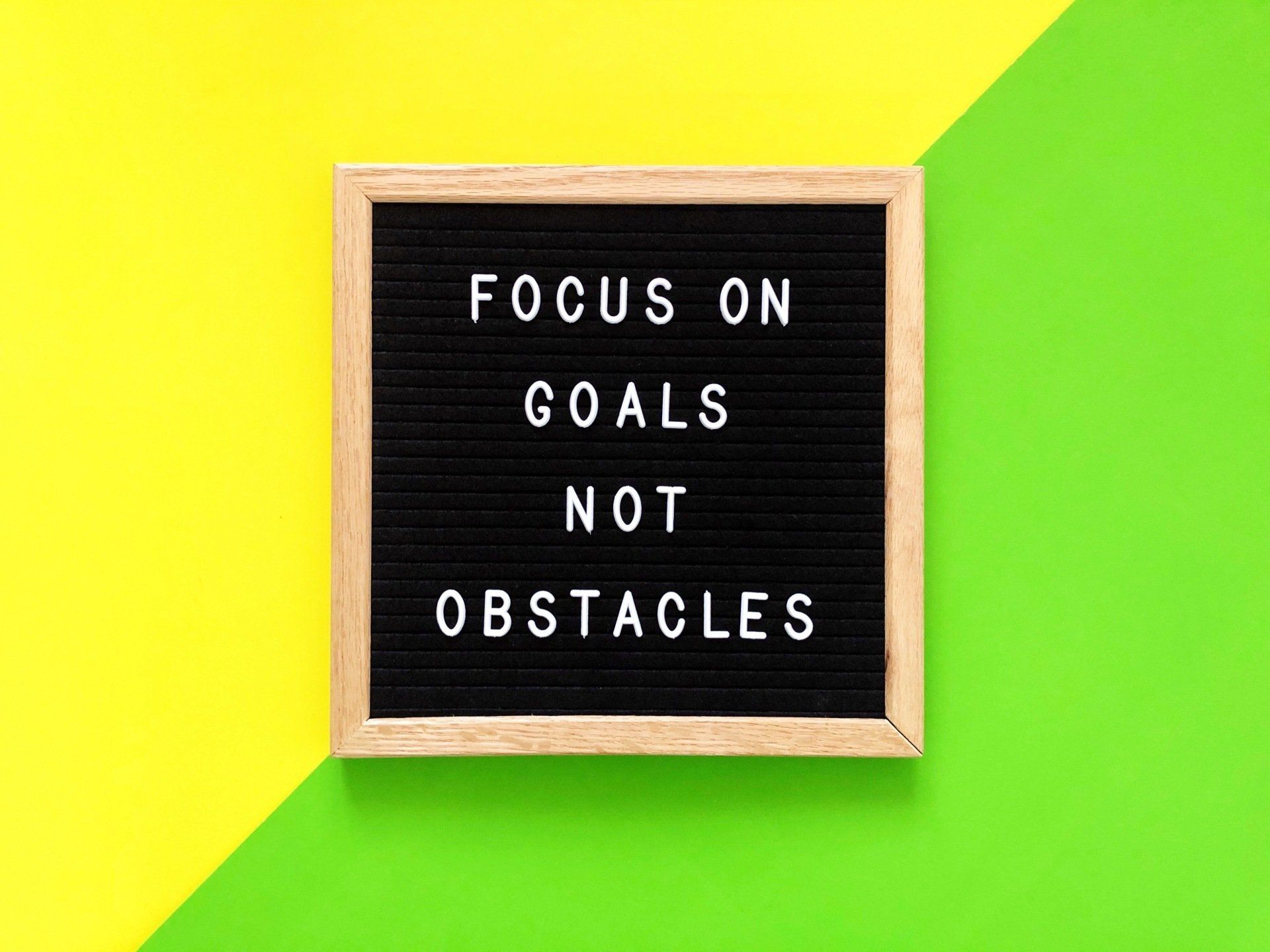 A black letter board with the words `` focus on goals not obstacles '' on a yellow and green background.
