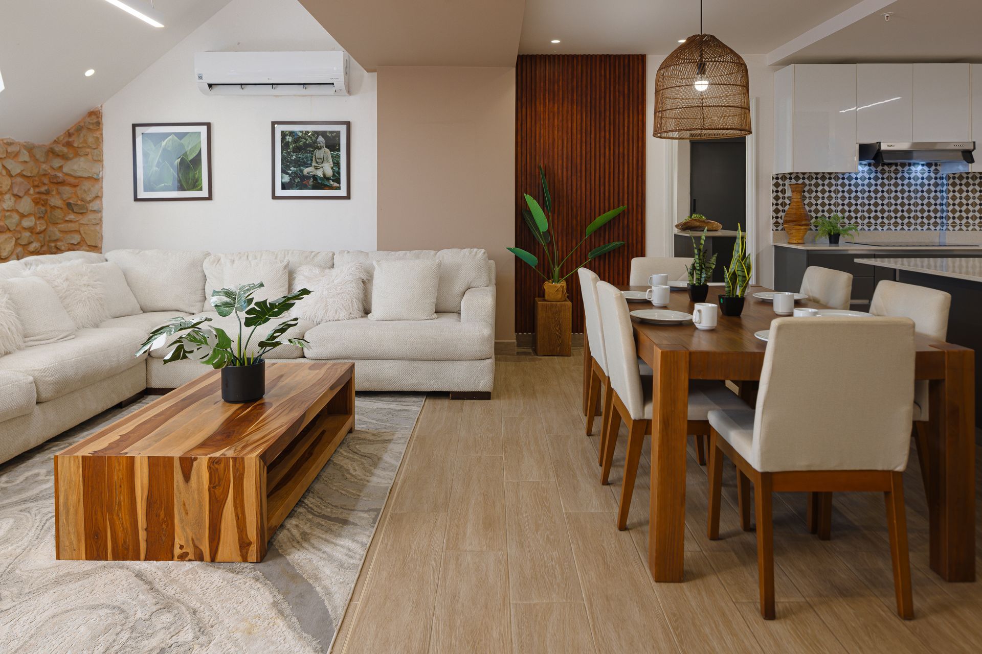 Open living and dining area at PH La Cuadra in Casco Viejo, photographed for Acomodo Rentals, with a cream sectional sofa, wooden furniture, and a woven pendant light.