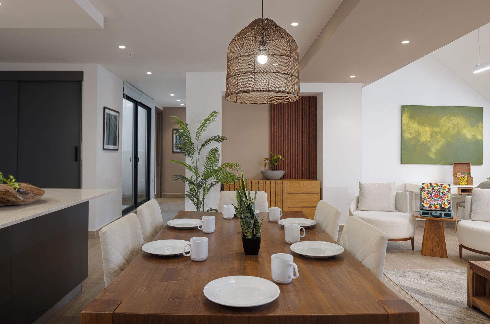 Dining area at PH La Cuadra in Casco Viejo, featuring a wooden table set with white plates and mugs, cream chairs, and a woven pendant light.