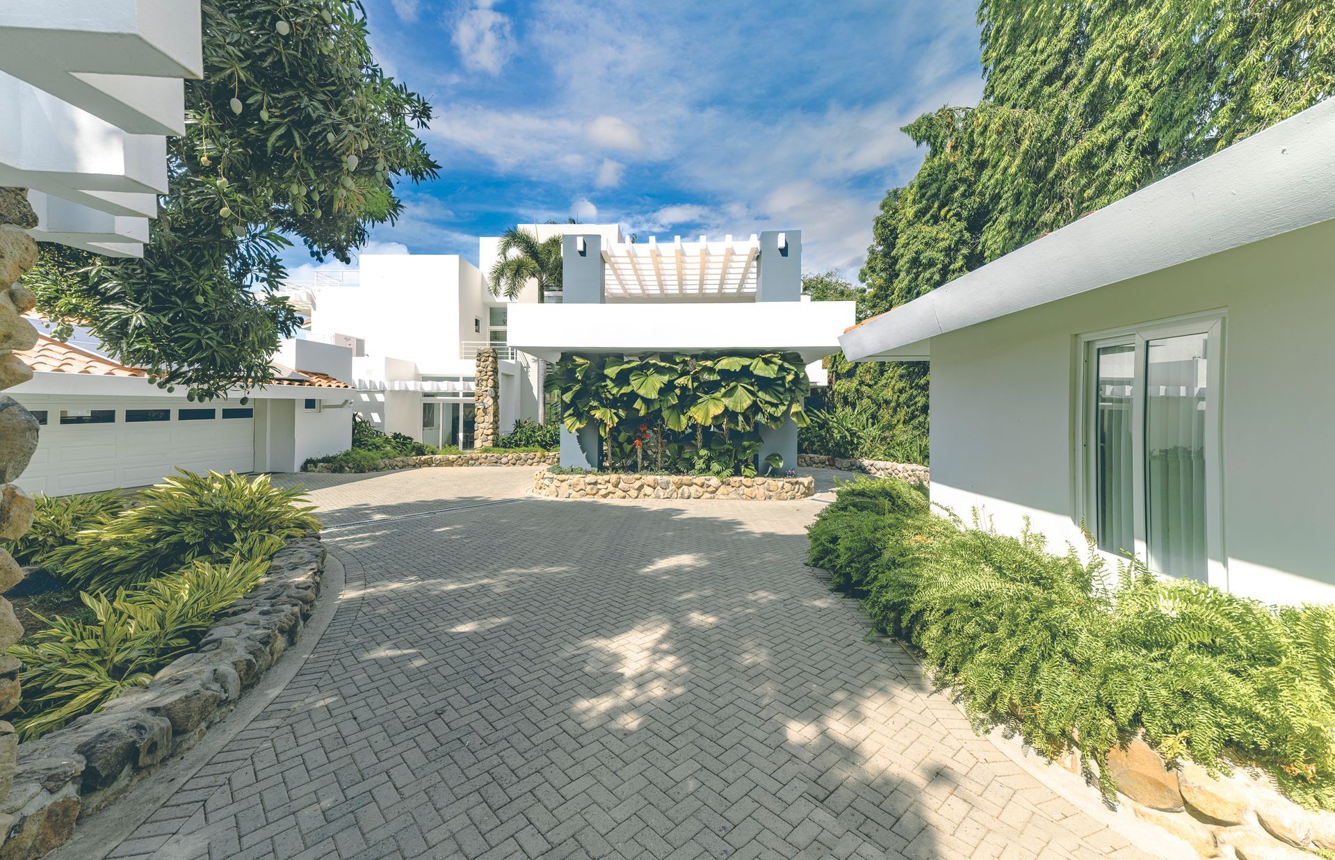 Manicured tropical driveway and modern white facade of an exclusive estate in Punta Barco, Panama Pacific Coast.