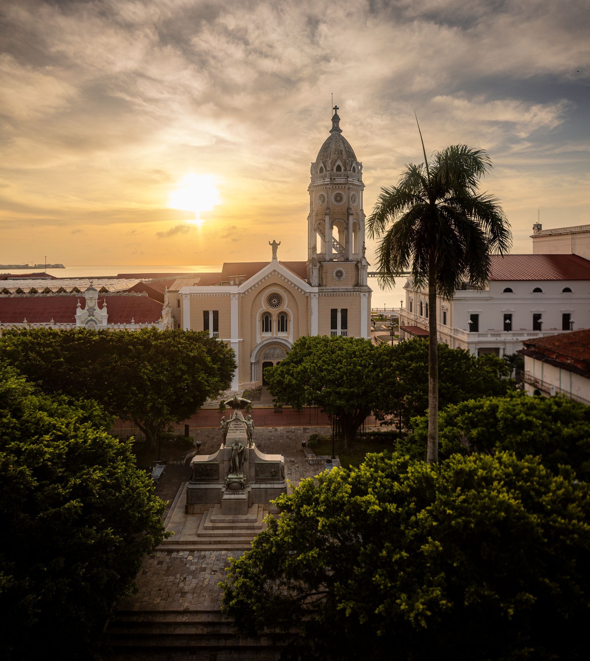 Plaza Bolívar and San Francisco de Asís Church viewed from PH Hotel Colombia, with a central monument, leafy trees, and golden sunlight over Casco Viejo.