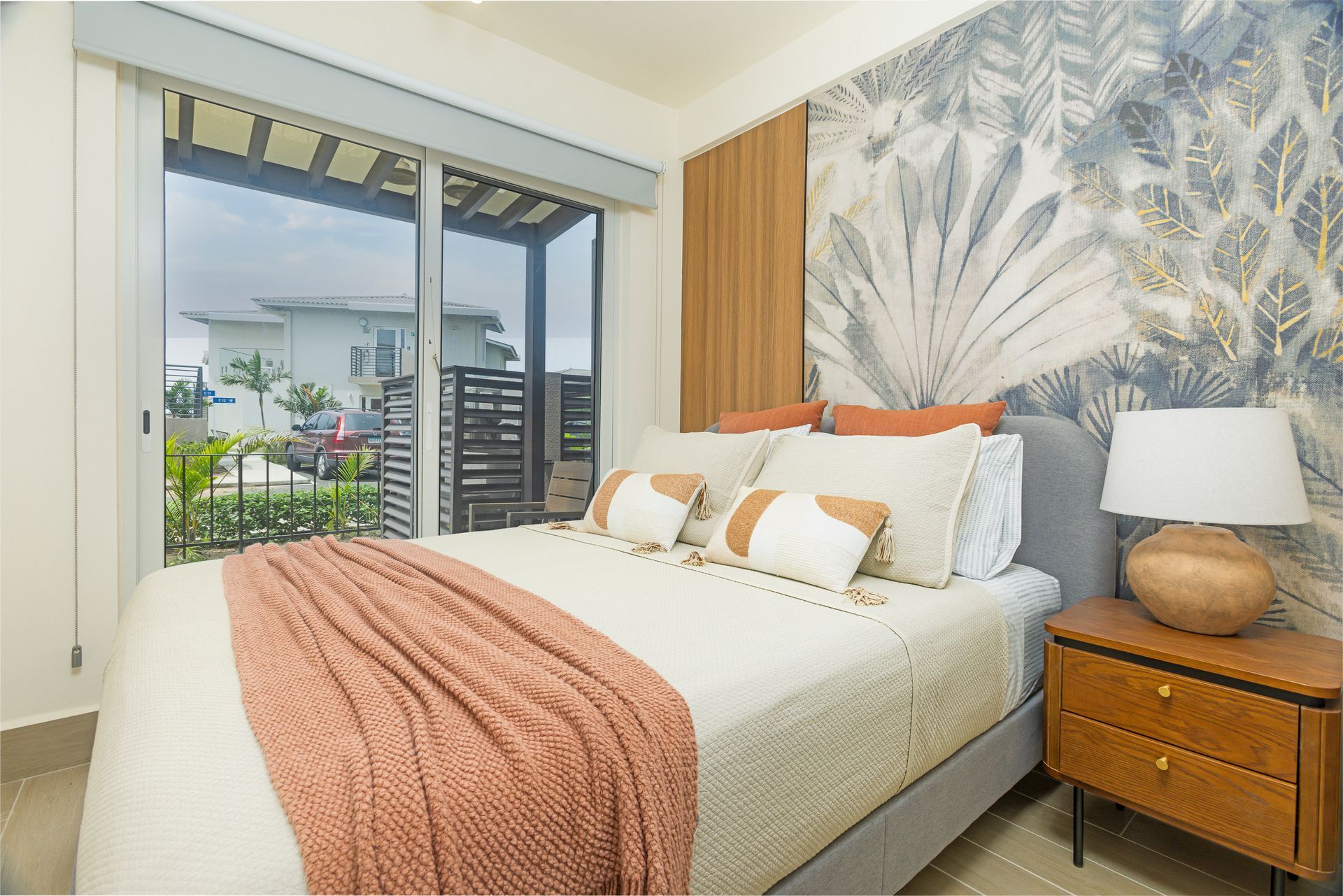 Coastal style bedroom interior with balcony access and palm leaf wall art in Playa Caracol, Panama..