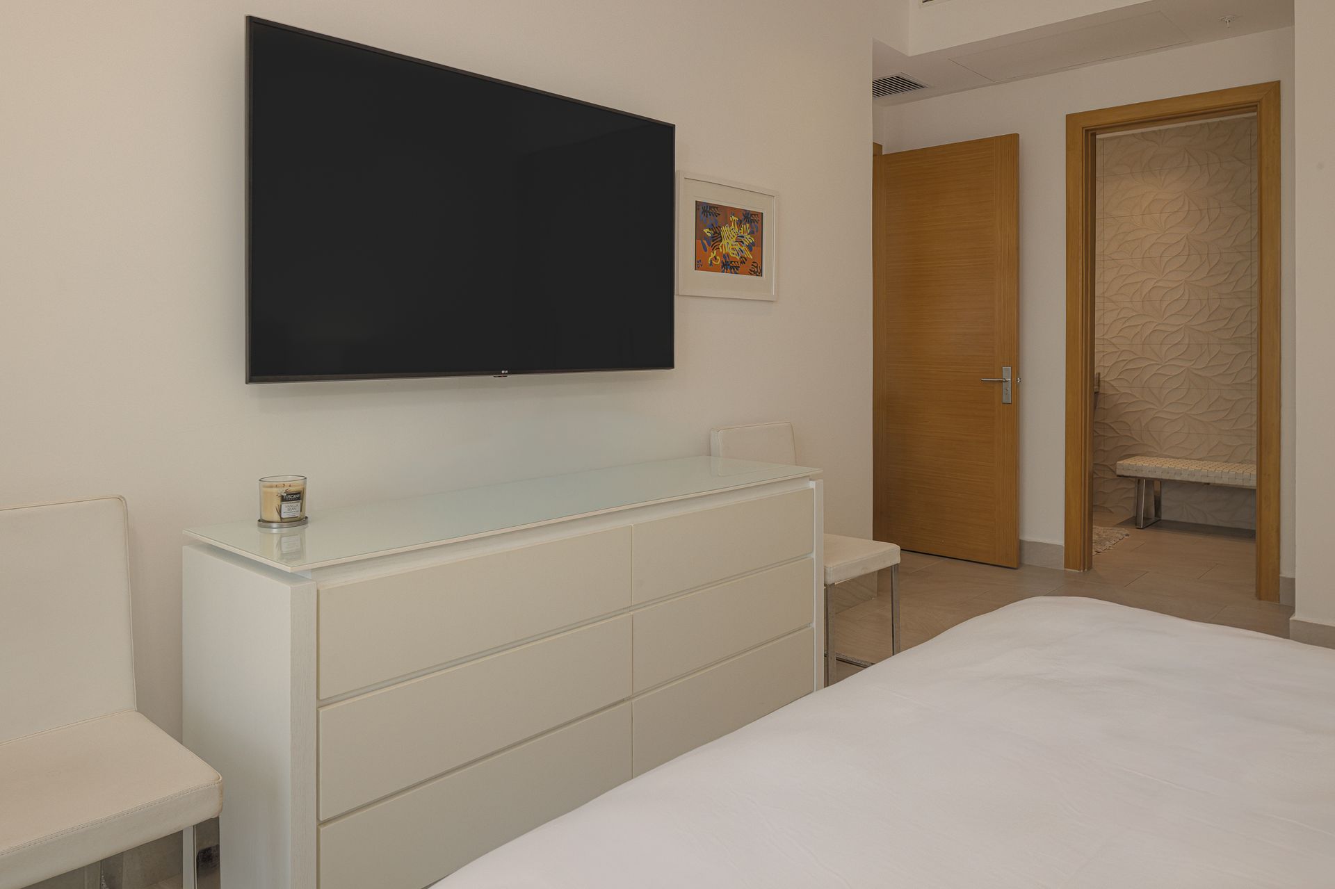 Bedroom with mounted TV and dresser at Playa Escondida apartment listed on Amazinn Places, Panamá