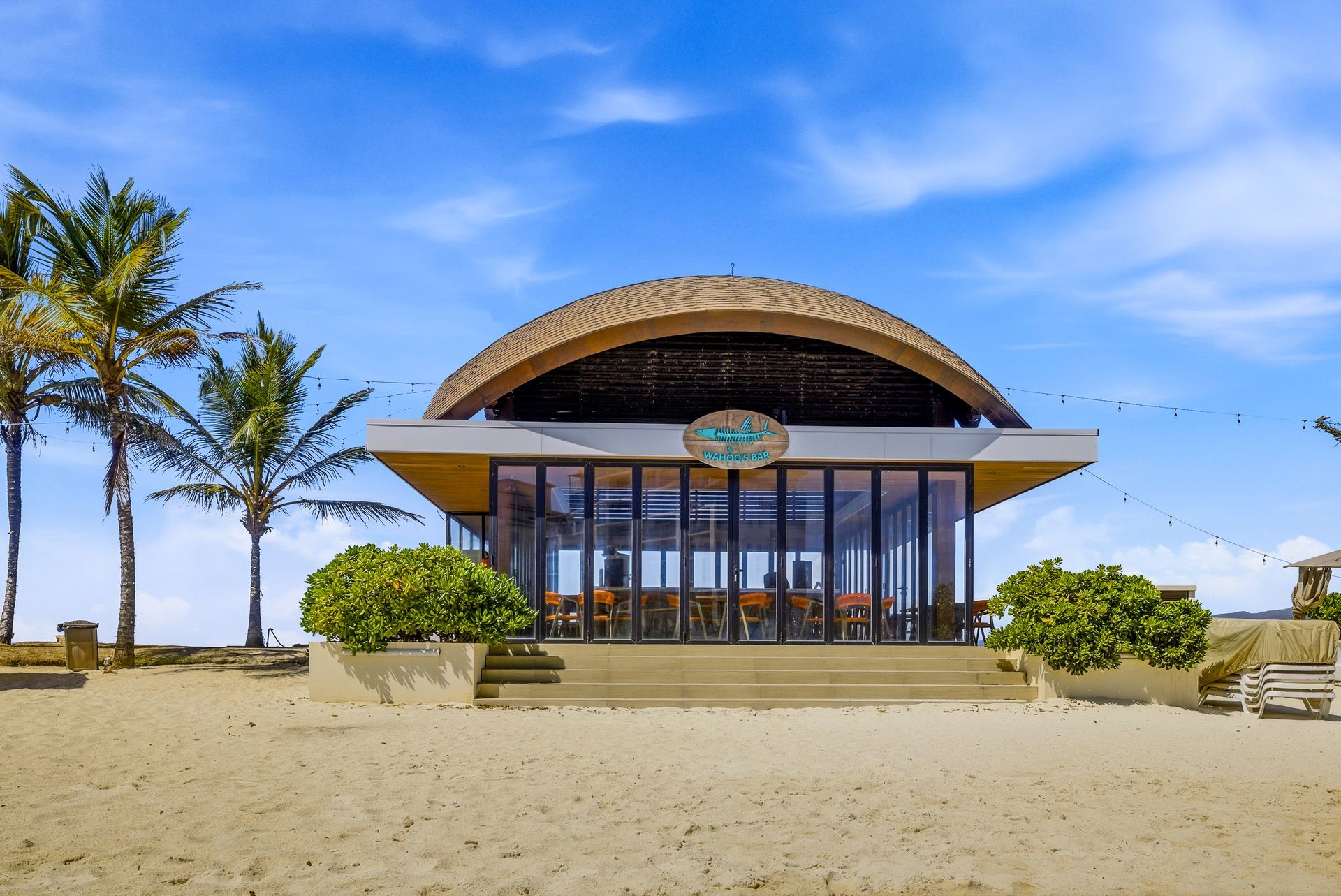 Beachfront restaurant with curved thatched roof on white sand at Playa Escondida Resort, Panama