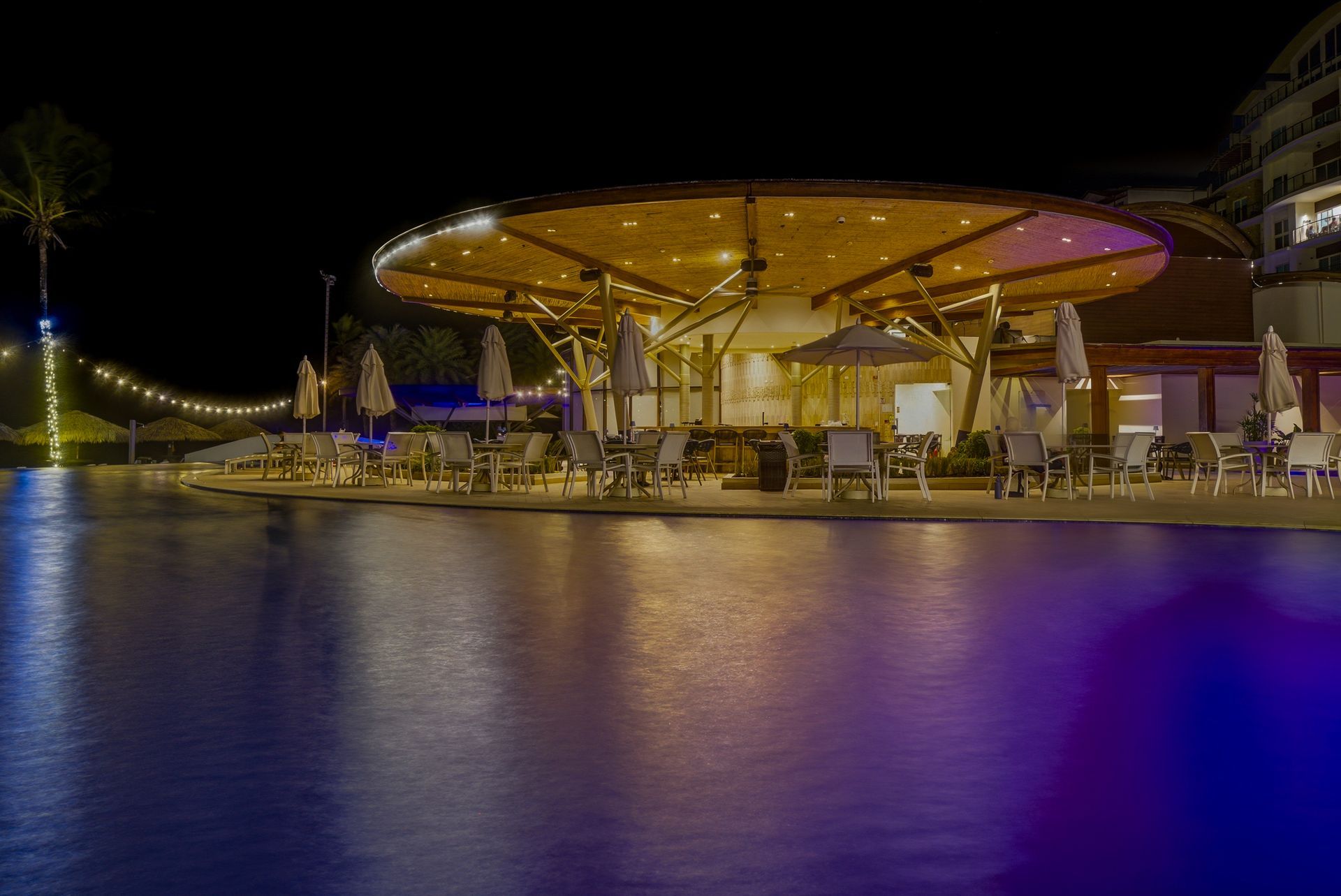 Illuminated circular beach club reflected on the pool at night, Playa Escondida Resort, Caribbean Panama