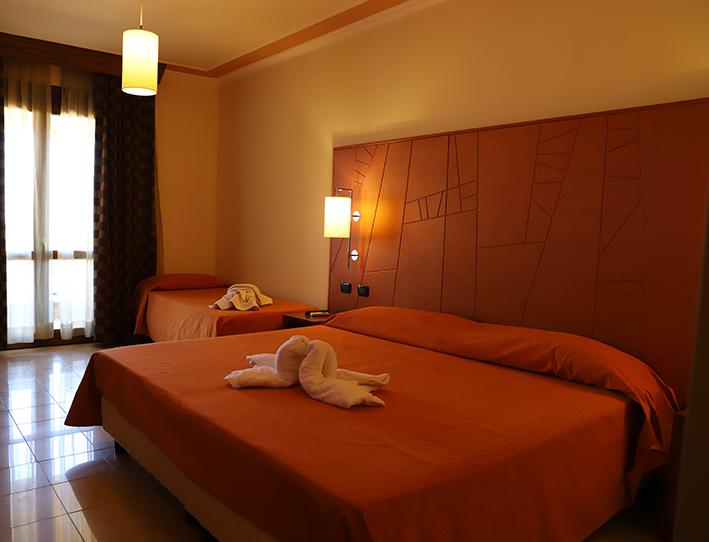 Una camera d'albergo con un letto grande e due letti più piccoli