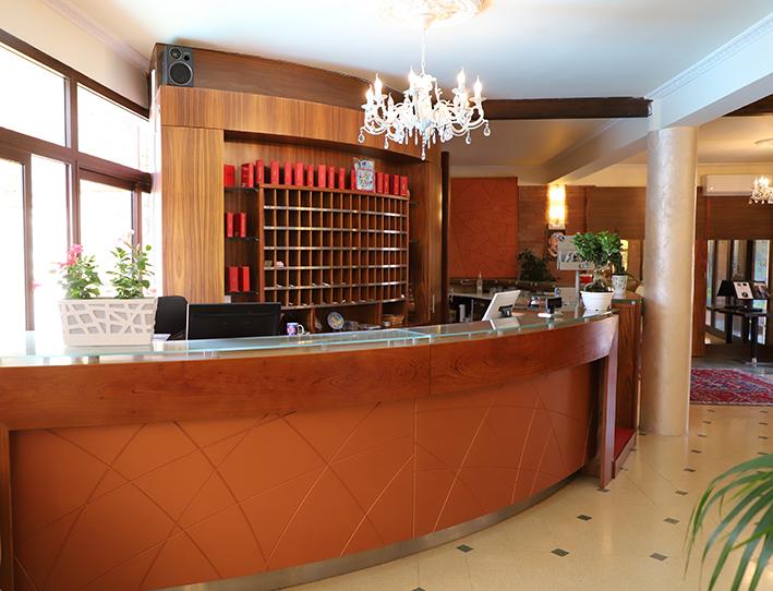 Una hall di un hotel con un lungo bancone di legno e un lampadario appeso al soffitto.