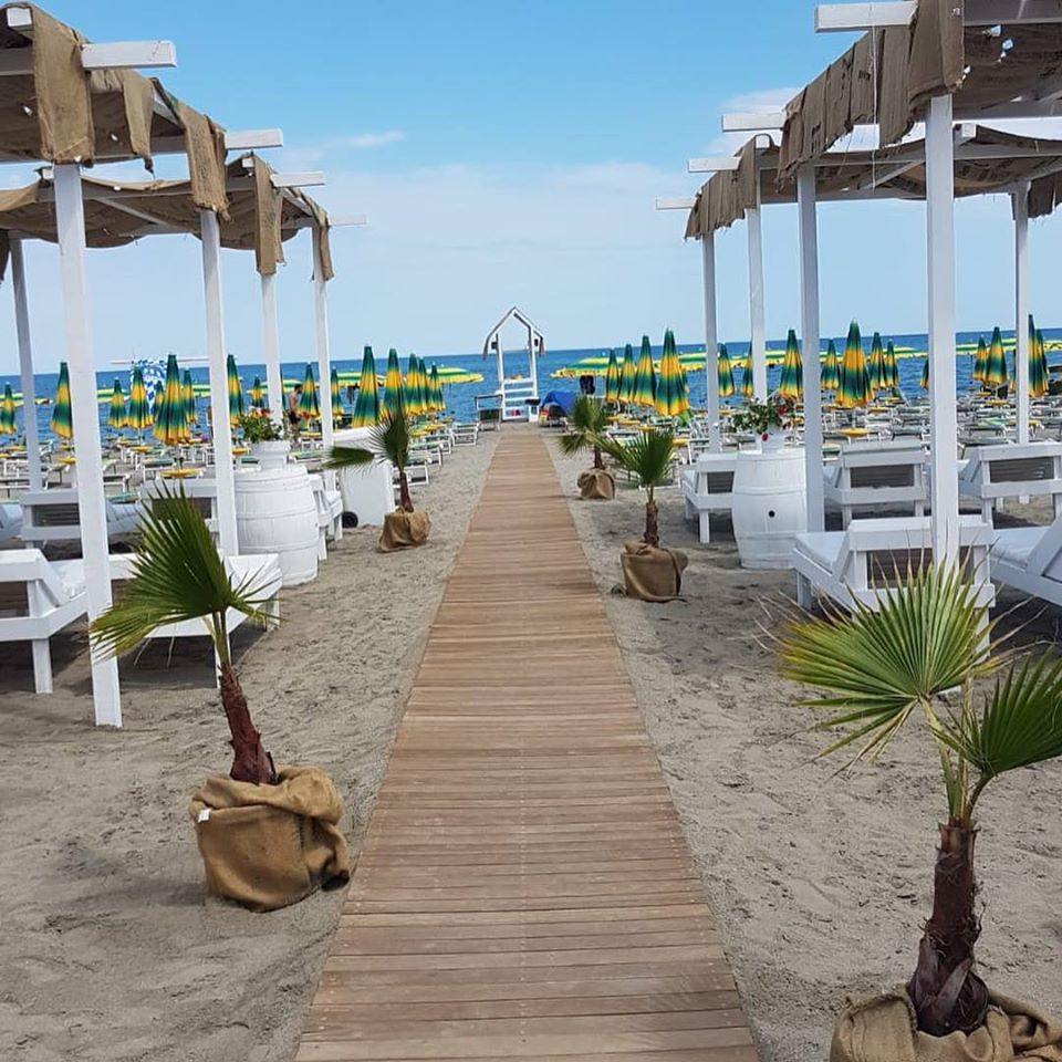 Una passerella di legno che conduce ad una spiaggia con ombrelloni
