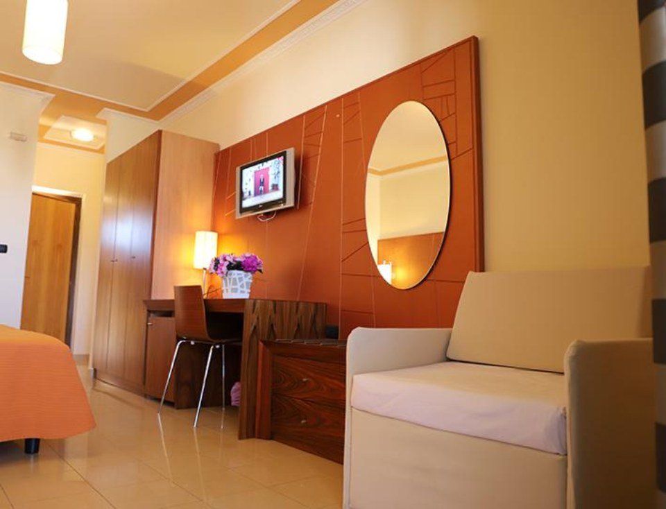Una stanza d'albergo con una sedia e una tv sul muro