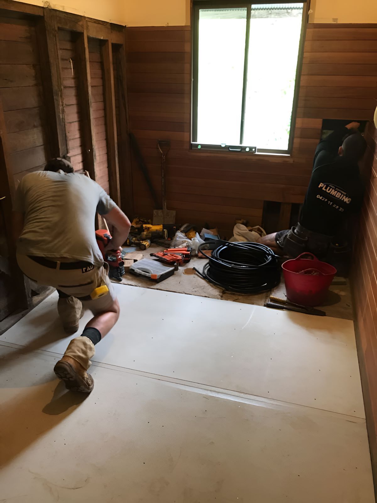 A Man Is Kneeling With Tools On The Floor Renovating The Bathroom — Coffs Coast Designer Bathrooms in Coffs Harbour, NSW
