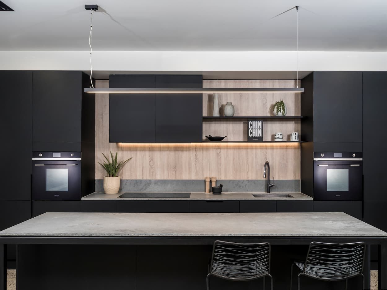 A Kitchen With Black Cabinets And A White Counter Top — Coffs Coast Designer Bathrooms in Toormina, NSW