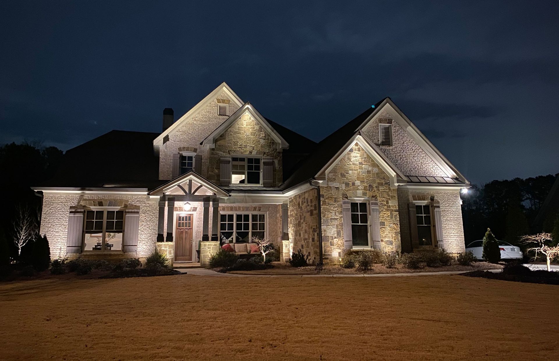 Stone house illuminated at night with outdoor lighting.