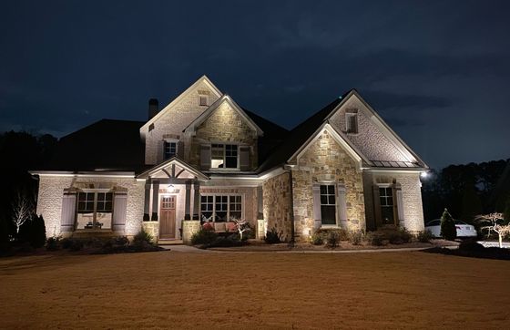 Stone house illuminated at night with outdoor lighting.