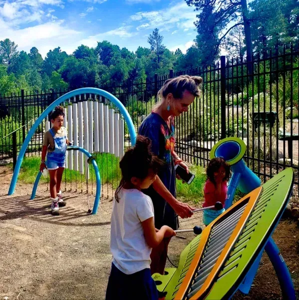A woman and two children are playing a musical instrument in a park