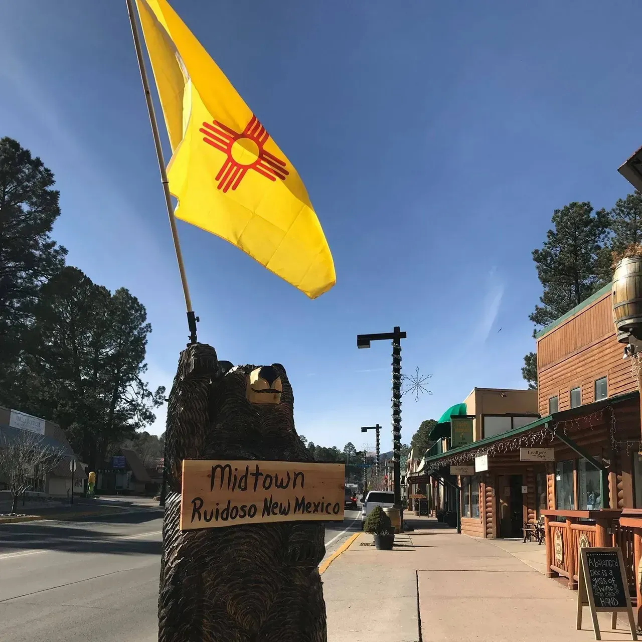 A yellow flag is flying over a sign that says midtown ruidoso new mexico