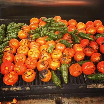 Tomatoes and peppers are being grilled on a grill