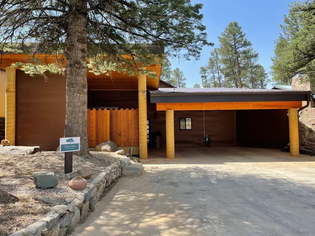 A house with a carport and a tree in front of it.