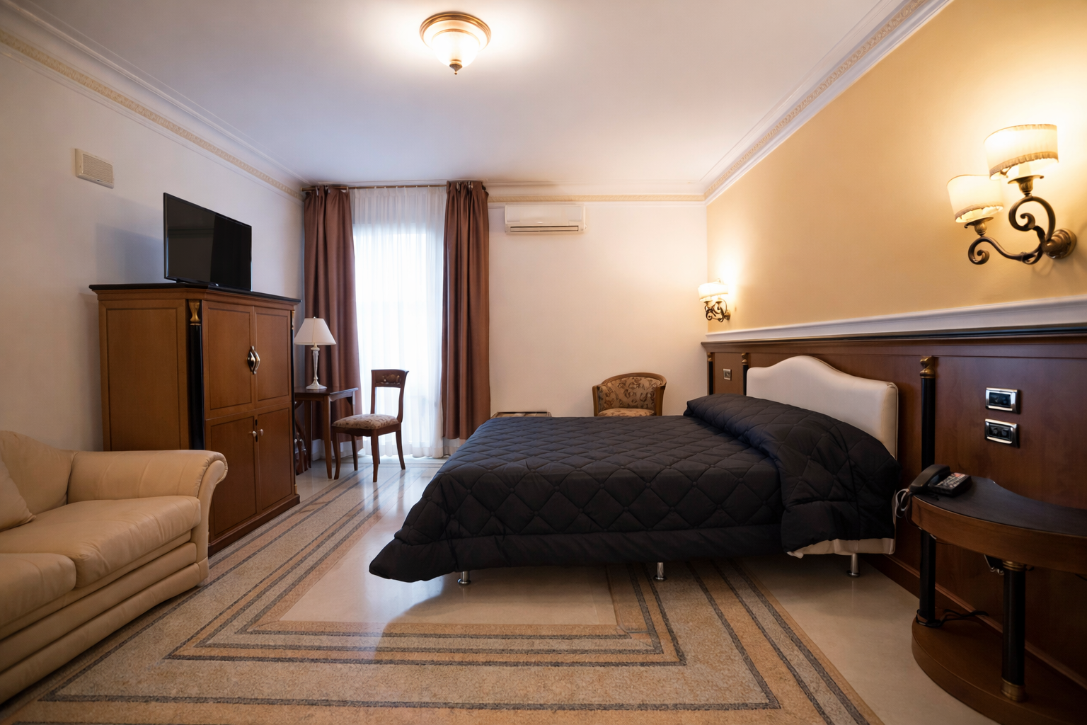 Camera d'albergo con letto, divano, TV e pavimento in marmo.