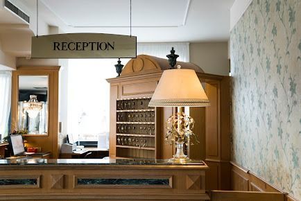 Banco della reception dell'hotel con mobili in legno, chiavi e una lampada sotto il cartello 