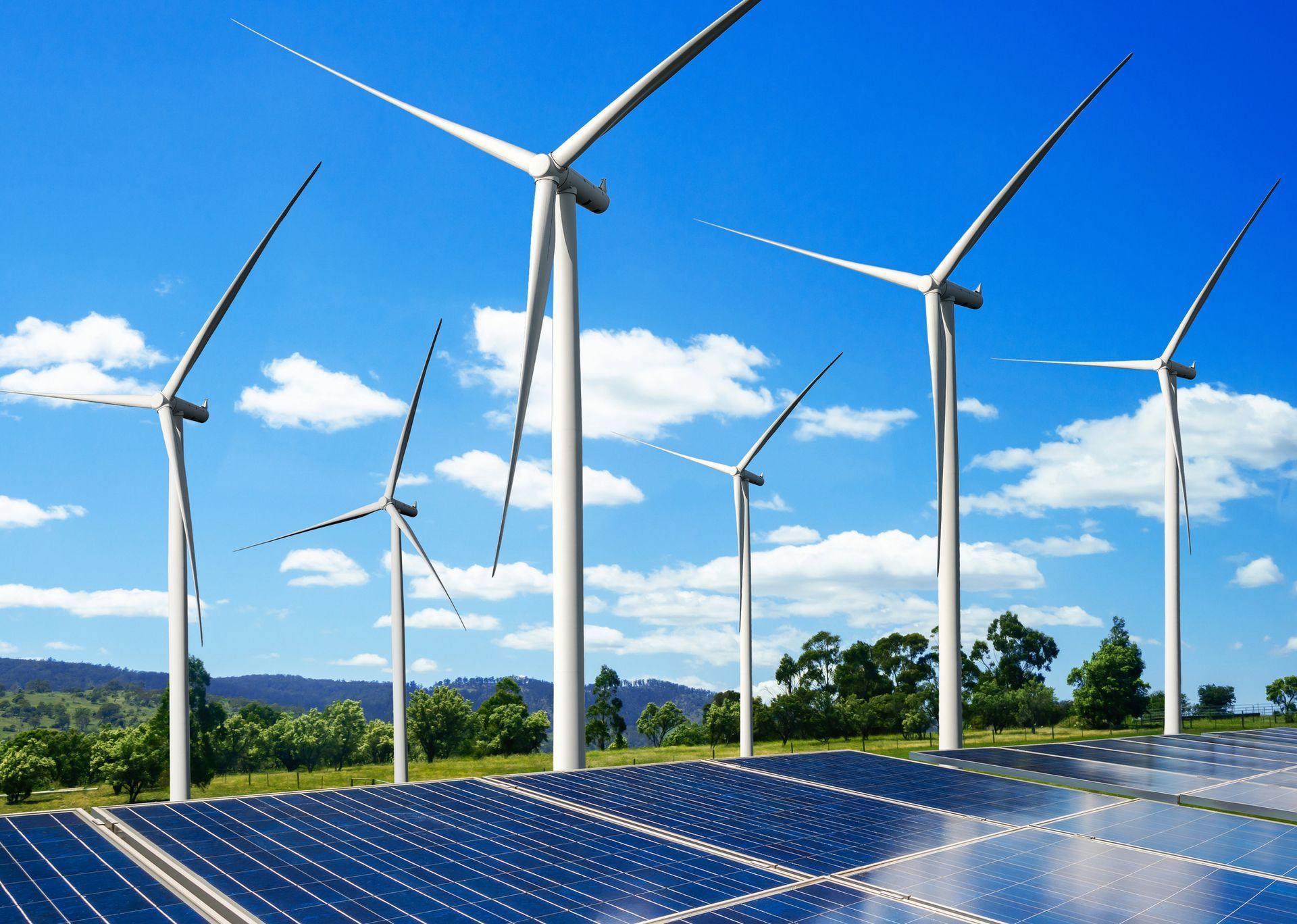 Turbine eoliche e pannelli solari generano energia sotto un cielo azzurro.