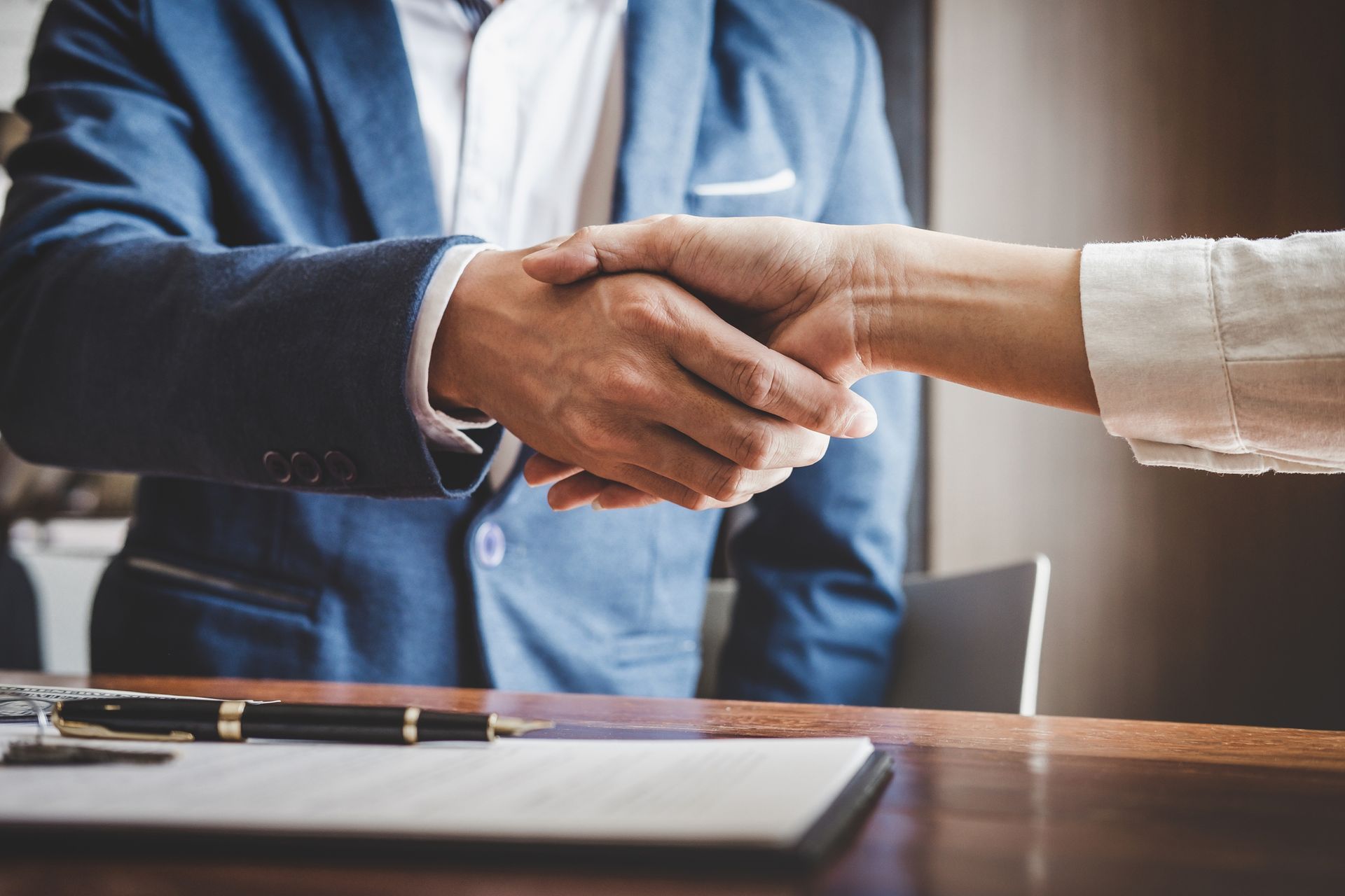 A man and a woman are shaking hands over a table.