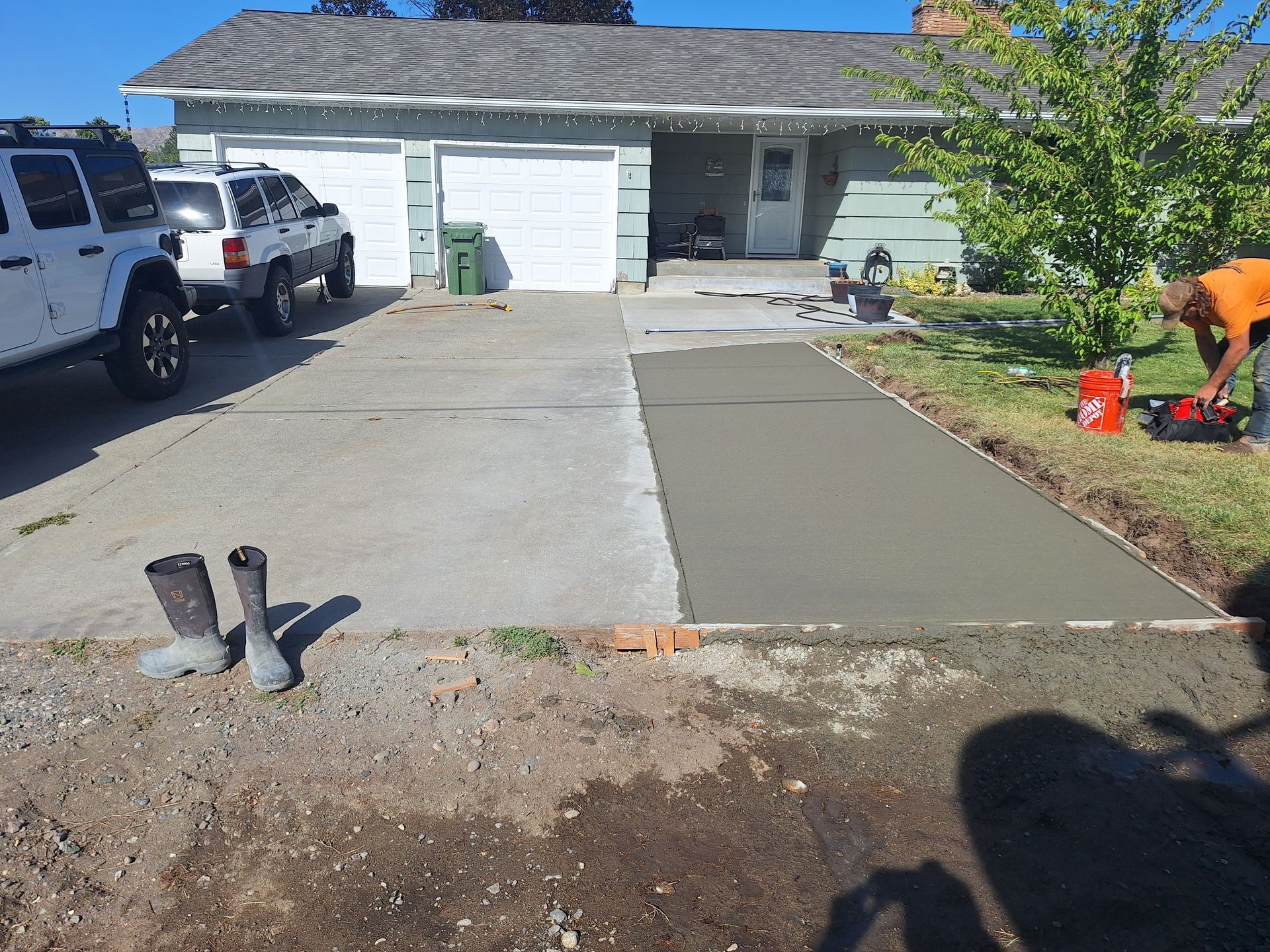 New concrete driveway being poured next to an older section; a person is working.