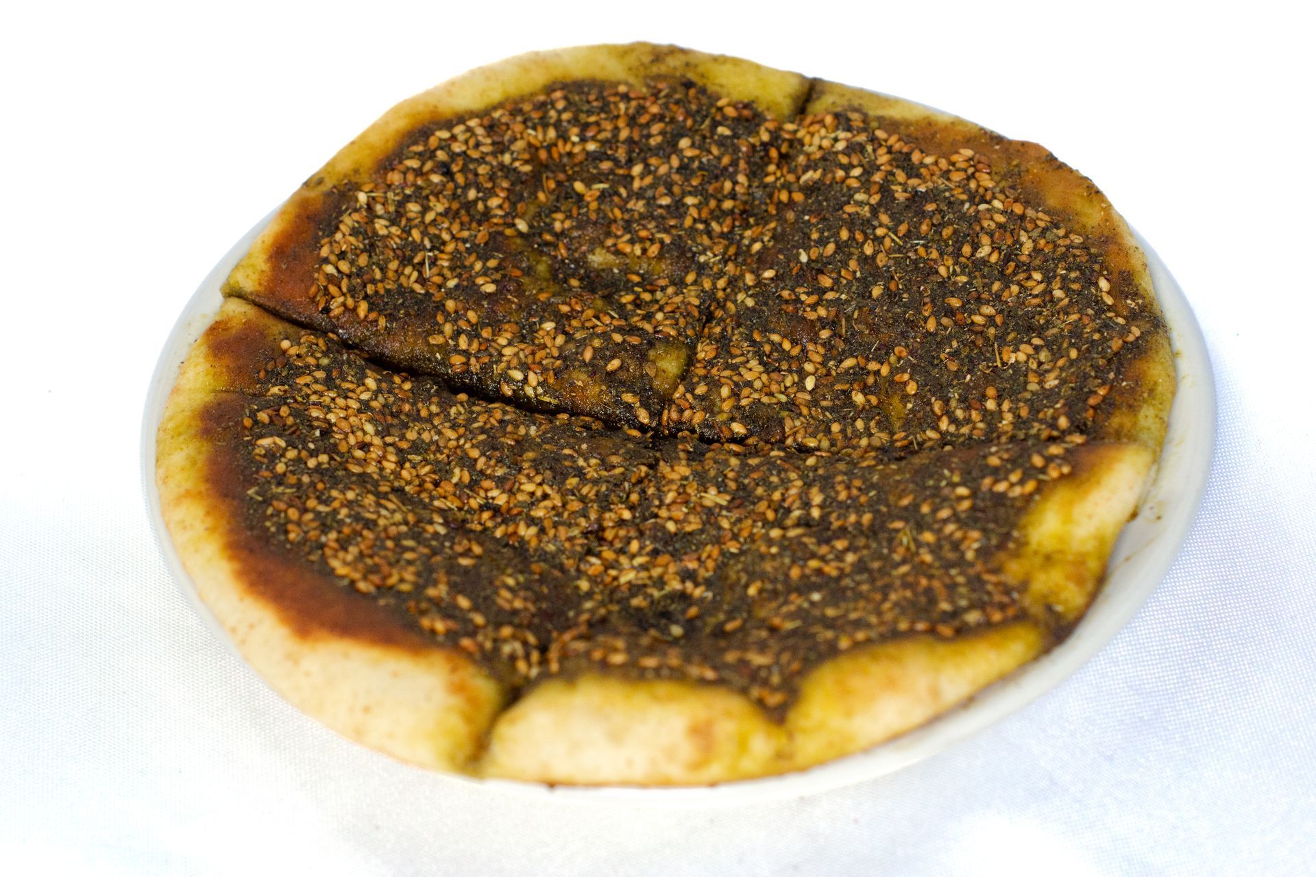 Zaatar pie (manakish ): baked thick pita topped w thyme olive oil sesame sees manakish or manoushe مناقيش