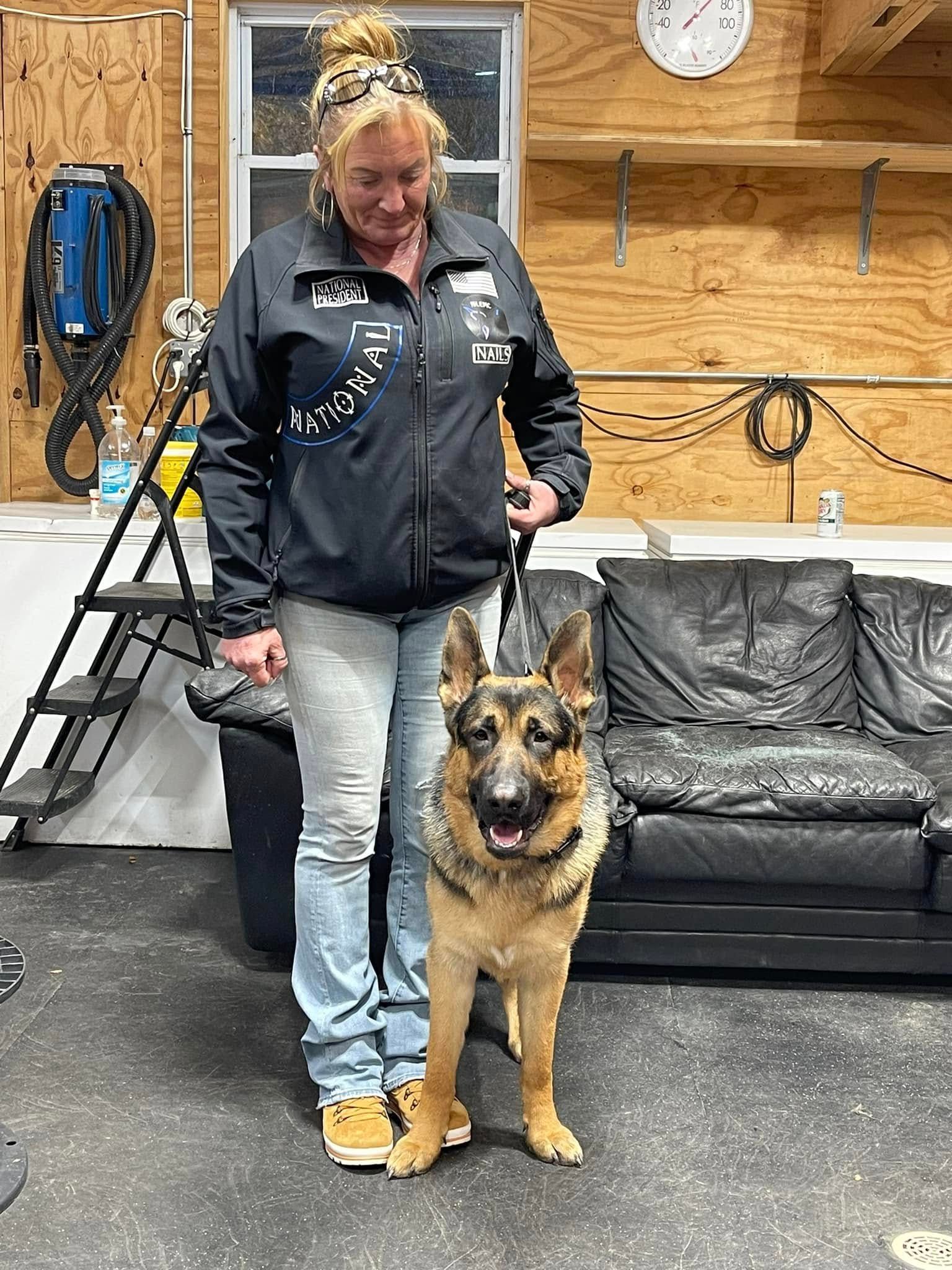 Woman standing with a German shepherd in a garage, both facing the camera.
