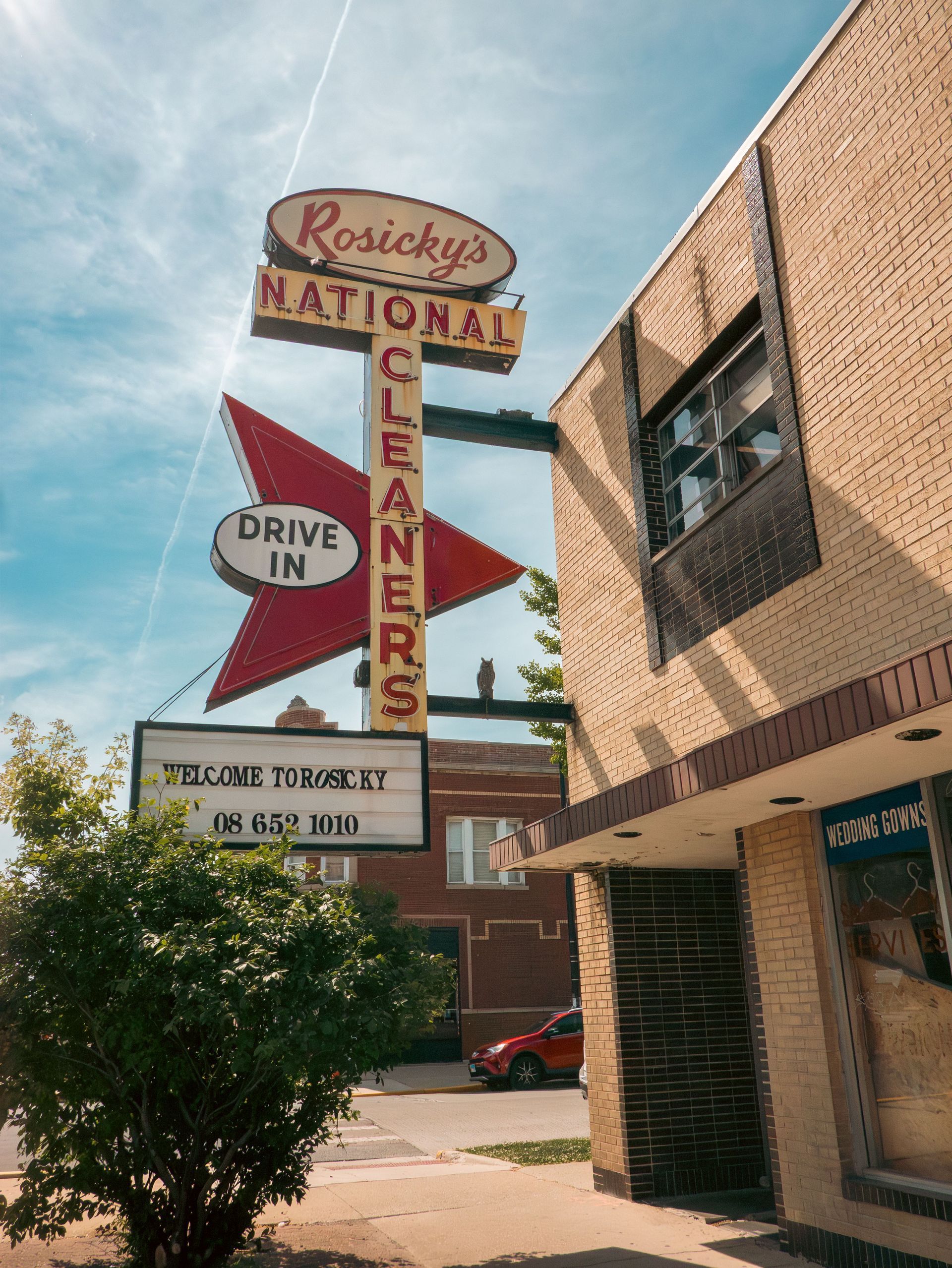 Rosicky’s National Cleaners sign with drive-in drop box beside a brick building under a blue sky