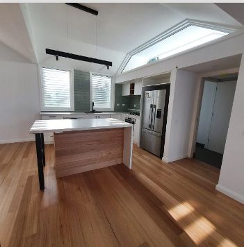 A kitchen with a large island and a stainless steel refrigerator | House Building Services | Clifton Springs