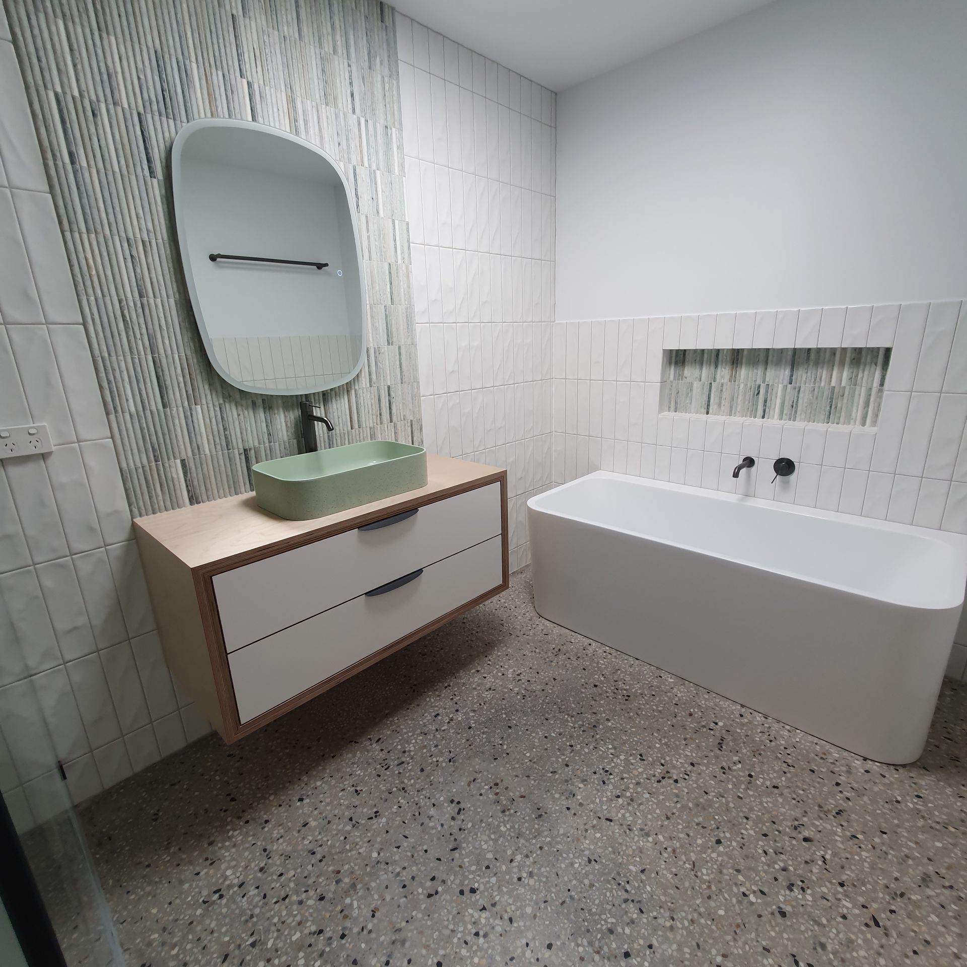 A bathroom with a bathtub , sink and mirror Building Services | Coastyle