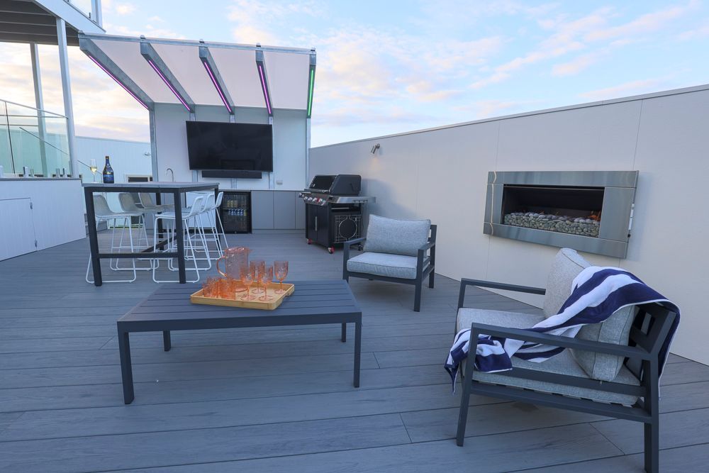 A patio with a fireplace , chairs , a table and a television.