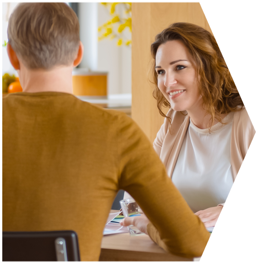 A man and a woman are sitting at a table and smiling at each other | House Building Services | Clifton Springs