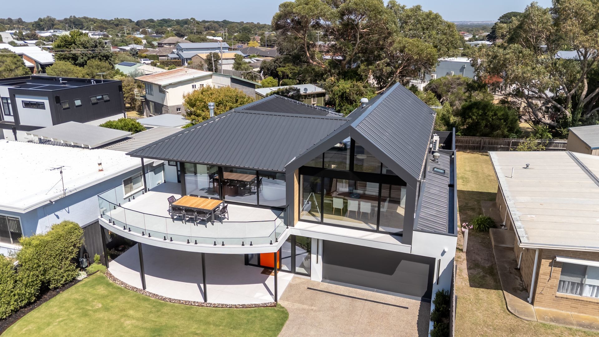 An aerial view of a large house with a large deck surrounded by trees.