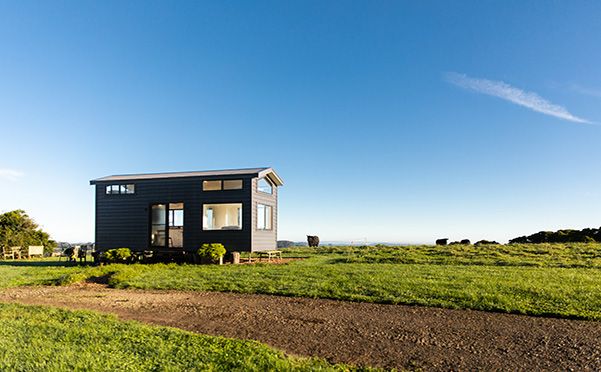 A small house is sitting in the middle of a grassy field | House Building Services | Coastyle