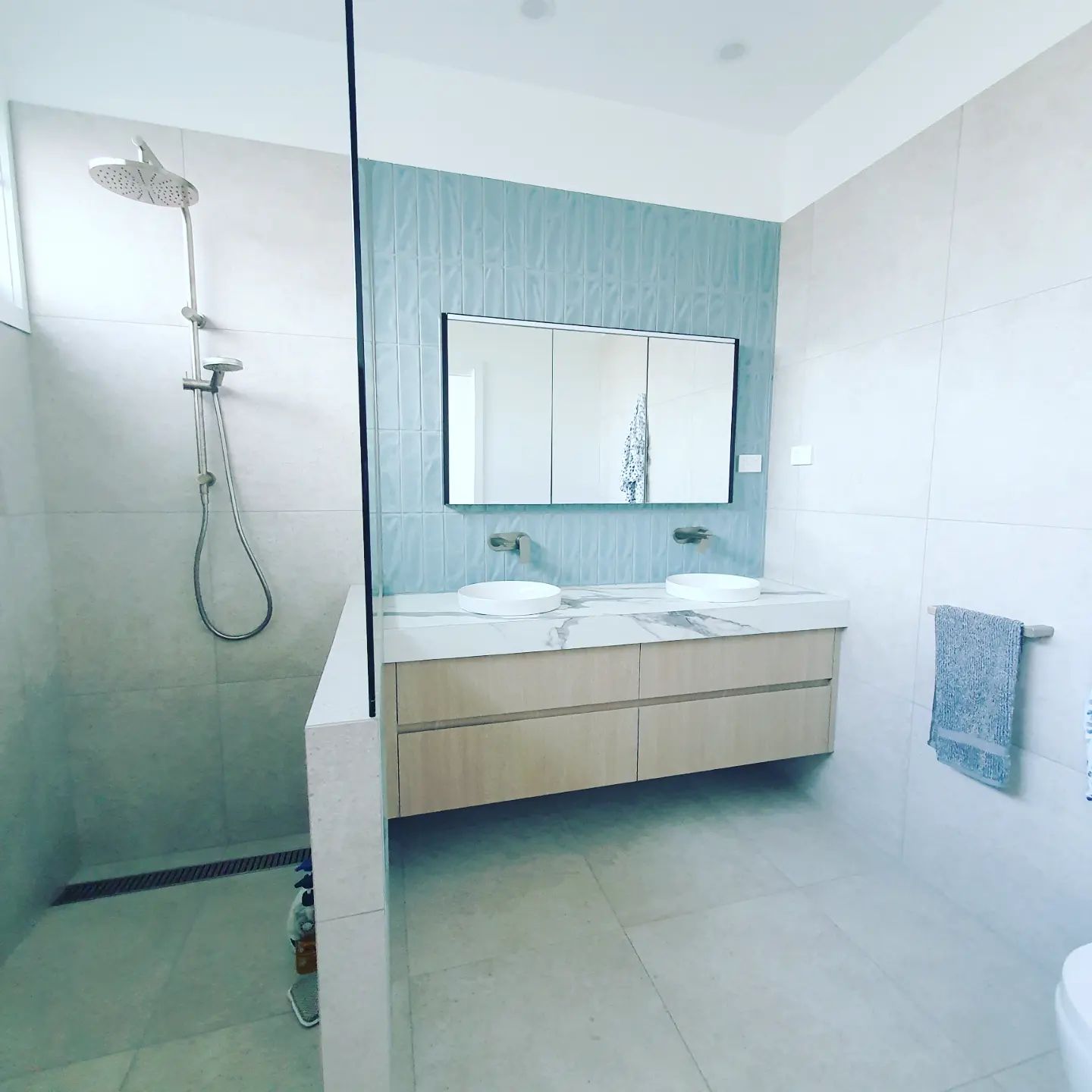 A bathroom with two sinks , a shower and a mirror  | Building Services | Coastyle