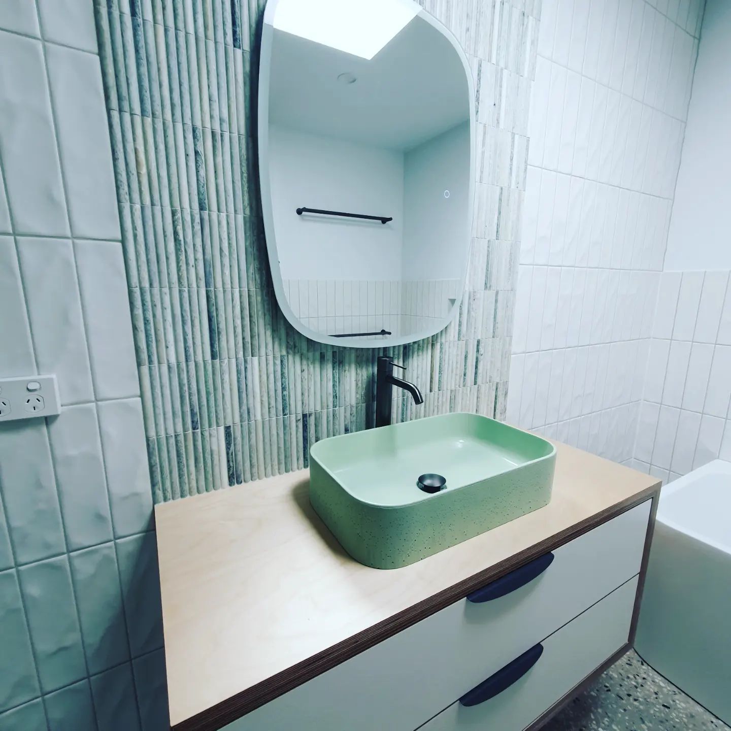 A bathroom with a green sink and a mirror | Building Services | Coastyle