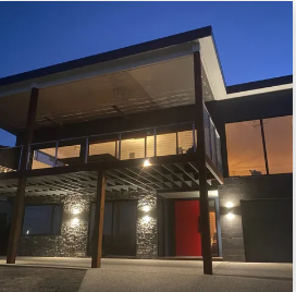 A large house with a red door is lit up at night | House Building Services | Clifton Springs