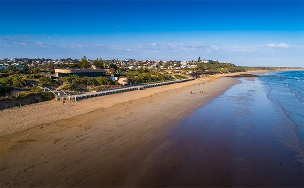 An aerial view of a beach with a pier in the background.