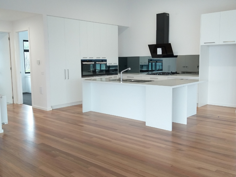 An empty kitchen with white cabinets and wood floors Building Services | Coastyle